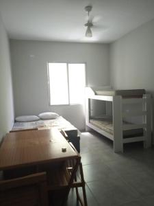 ein weißes Zimmer mit einem Tisch und einem Etagenbett in der Unterkunft Studio na Biquinha em São Vicente in São Vicente