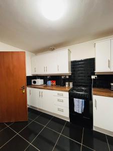 a kitchen with white cabinets and a black tile floor at CityZen - serviced accomodation in Birmingham