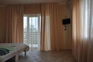 a bedroom with a bed and a window with curtains at Inn Estio in Zatoka
