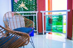 Una silla de ratán sentada en un balcón junto a una ventana. en K-suites A07 - Appartement 1 chambre près de la mer, en Pointe-Noire