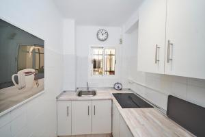 eine Küche mit Spüle und einer Uhr an der Wand in der Unterkunft Cielo Azul in Nerja