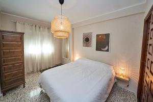 ein Schlafzimmer mit einem weißen Bett und einem Kronleuchter in der Unterkunft Cielo Azul in Nerja