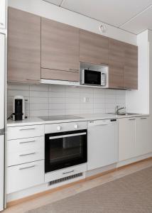 a kitchen with white cabinets and a microwave at Stylish, 450 m walk to the Estonian ferry, Free parking and balcony in Helsinki