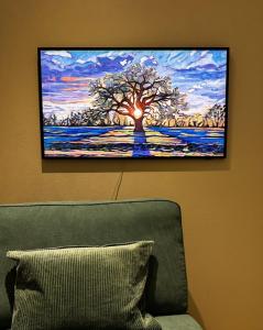a painting of a tree on a wall next to a couch at Stylish, 450 m walk to the Estonian ferry, Free parking and balcony in Helsinki +10 photos