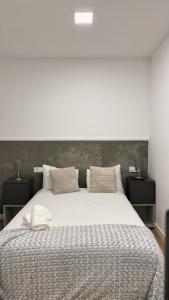 Un dormitorio con una gran cama blanca con dos mesitas de noche. en APARTAMENTOs TURÍSTICOS PLAZA ATOCHAS # 4, en A Coruña