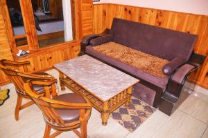 a living room with a couch and a table and chairs at Anurag Hotel Chakrata in Chakrāta