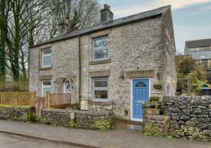 an old stone house with a blue door at Luxurious Cosy Cottage in Buxton
