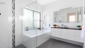 a white bathroom with a sink and a mirror at Marine Adventures in Callala Bay