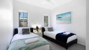 two beds in a bedroom with white walls and windows at Marine Adventures in Callala Bay +38 photos