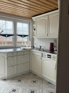 La cuisine est équipée de placards blancs, d'un évier et de fenêtres. dans l'établissement Ferienwohnung Ruppbergblick, à Zella-Mehlis 9 autres photos