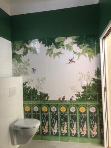 a bathroom with a toilet and a green and white wall at Les Haltes du Clos du Petit Dannezy in Cour-Cheverny