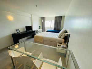 a hotel room with a bed and a desk at Ritz Paradise Beira Mar no Hotel Ritz Suítes in Maceió