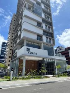 a large apartment building with a sign on it at Simple Smart Residence in Tambaú