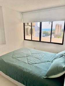 a bedroom with a bed and a window with a beach at Internacional Hermoso y Céntrico in Santa Marta