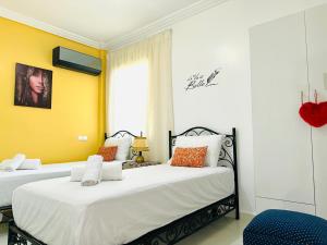 two beds in a room with yellow walls at Appart F3 de luxe à Gueliz - 5 min de la gare - Piscine, WiFi, parking au coeur de Marrakech in Marrakech