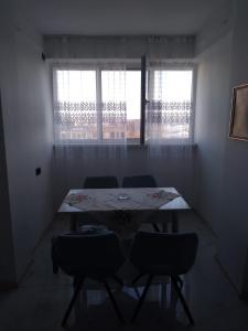 mesa y sillas en una habitación con 2 ventanas en Garsonieră confort 1, en Buzau