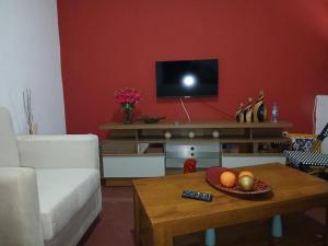 ein Wohnzimmer mit einem Sofa und einem Tisch mit einem TV in der Unterkunft Mille Nuits Appartement in Tarrafal