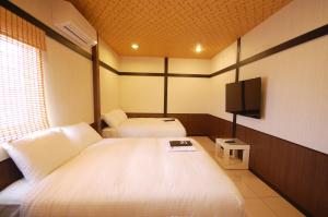 a hotel room with two beds and a flat screen tv at Hananoi Bed and Breakfast in Hengchun