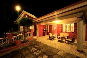a patio at night with two chairs and a table at The Red House in Ooty