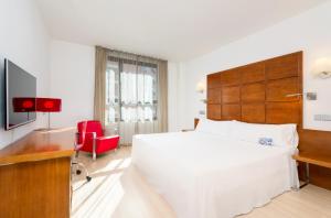 um quarto com uma grande cama branca e uma cadeira vermelha em Hotel Zentral Ave em Saragoça