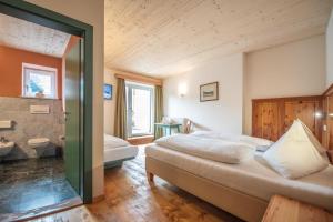 a bedroom with two beds and a bathroom at Hotel Gassenwirt in Chienes +70 photos