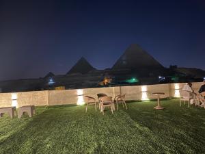 a group of chairs and tables on the grass with pyramids at Isis Pyramids View Inn in Cairo