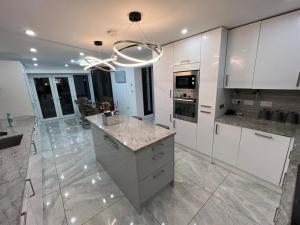 a large kitchen with white cabinets and a chandelier at Vancouver Place in Orpington