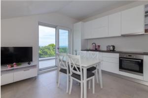 a white kitchen with a dining table and a large window at Studioapartman Pink Živogošće in Živogošće
