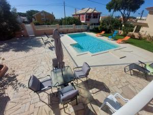 eine Terrasse mit Stühlen und Sonnenschirm und ein Pool in der Unterkunft Casa Maria in São Domingos de Rana