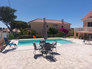 eine Terrasse mit Tisch und Stühlen neben einem Pool in der Unterkunft Casa Maria in São Domingos de Rana