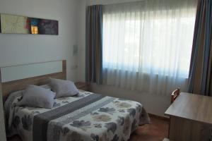 a small bedroom with a bed and a window at Hostal El Trovador in Altea