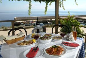 einen Tisch mit Teller mit Speisen und Weingläsern darauf in der Unterkunft Pharos Rooms in Region Ilia