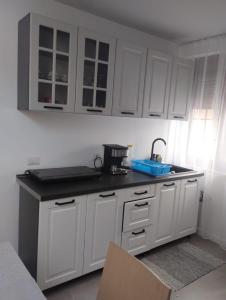 a kitchen with white cabinets and a black counter top at Casa Mont Blanc Cavnic apartament 2 in Cavnic +3 photos