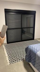 a person holding a remote control in front of a bedroom at Refúgio nascer das águas in Gravatal