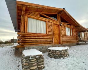 a log cabin in the snow with two stools at cabañas MERAKI in Uspallata