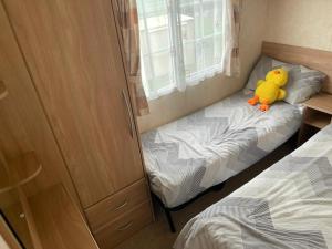 a yellow stuffed duck sitting on a bed in a bedroom at OV19- Wind in the willow summer house in Heysham