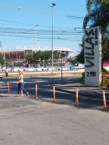 里约热内卢Alugo Suítes de luxo - Parque olímpico的一名女子沿着街道走在路标旁