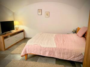 a bedroom with a pink bed and a television at Farmhouse -Alter Sandwirt- in sunny Carinthia in Vorderberg