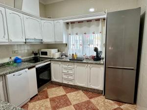 a kitchen with white cabinets and a stainless steel refrigerator at La Casa del Flamenco in Cañada del Rabadán