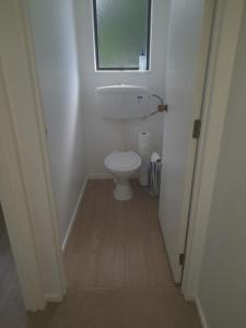 a small bathroom with a toilet and a window at Cosy Unit 3 bdrms Two dogs live onsite with me in Waipapa