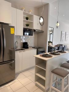 a kitchen with white cabinets and a stainless steel refrigerator at Elegant Modern Tiny Home in San Miguel +7 photos