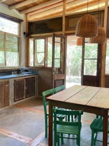 Una cocina con una mesa de madera y sillas verdes. en Casa LaMora, en San Marcos Sierras