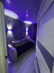 Sofá en habitación con iluminación púrpura en Pelivan Studio, en Chişinău