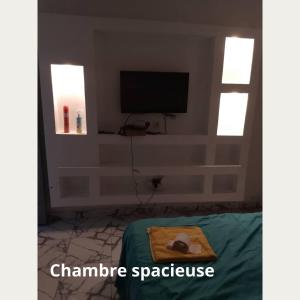 een woonkamer met een tv en een bed met bij Fôhundi home in Abidjan