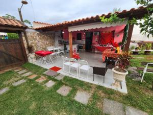 a patio with chairs and a table in a yard at Casa da Dinda à 650m da praia de Itaúna in Saquarema