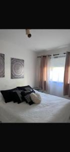una camera da letto con un letto con cuscini neri e una finestra di Apartamento en punta del este a Punta del Este