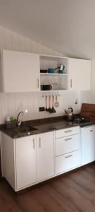 a kitchen with white cabinets and a counter top at Tinys Abedul in Lago Meliquina