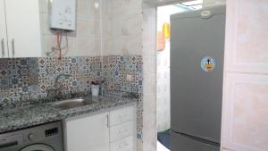 a kitchen with a sink and a refrigerator at appartement central plein d’expérience in Martil +10 photos
