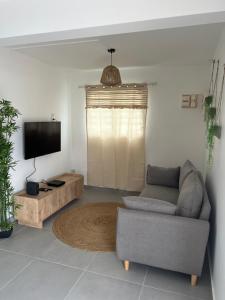 a living room with a couch and a flat screen tv at Casa Caraïbe in Les Trois-Îlets