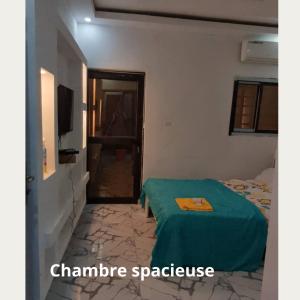 een slaapkamer met een bed met een groene deken bij Fôhundi home in Abidjan